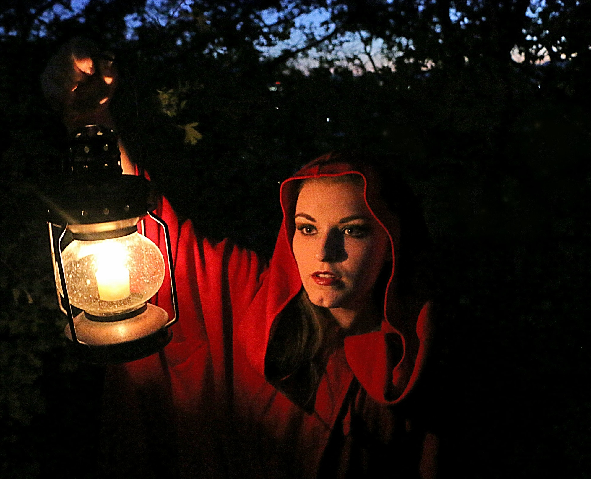 fairytale-portrait-of-woman-in-red-hood-holding-lighted-lantern-as-she-enters-dark-woods-.jpg